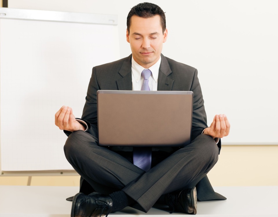 angajat in sezut, care face yoga cu un laptop pe picioare